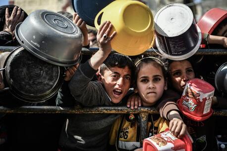 Mohammad, 11, and Reham, 9, stand at a food distribution center in Rafah, southern Gaza Strip.