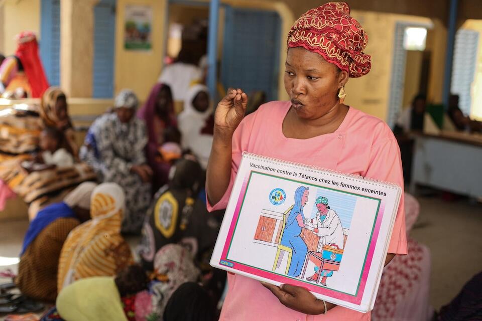 Holding a book of illustrations, Kadidia Cissé, a midwife in Mali, raises awareness of the importance of tetanus vaccination among pregnant women and women of child-bearing age.