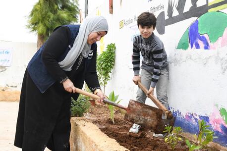 A mother and her son in Jordan plant vegetation at a Climate Action Club.