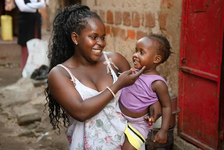 Esther, 16, holds her 2-year-old daughter Amira Jemima outside their rented one-room house in Katanga Kampala, Uganda, on March 5, 2024.
