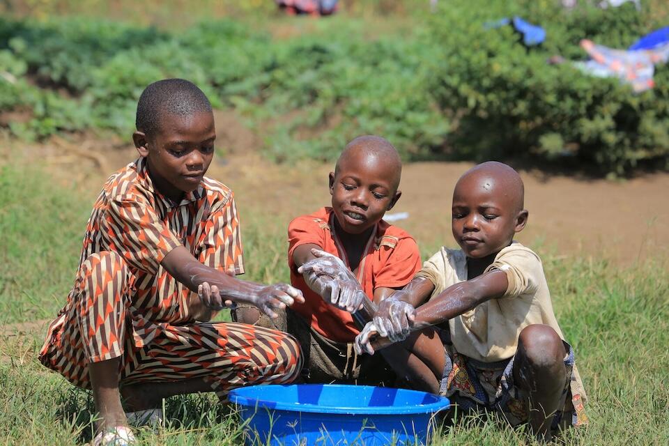 Three children sit washing their hands in Lokalis village, Lokalis subcounty, Amudat district, Uganda.