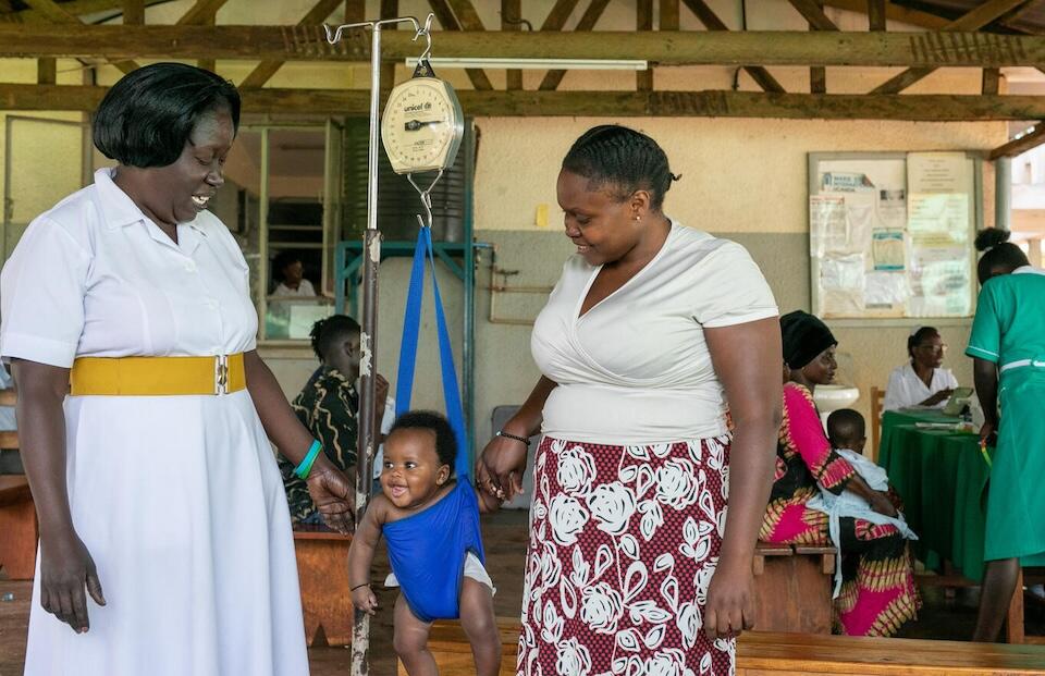 A nurse weighing a baby while the mother looks on at Jinja, a UNICEF-supported referral hospital in eastern Uganda.