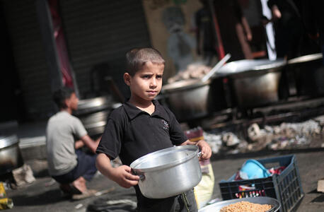Abdul, 8, in Rafah city, Gaza, heads to a food distribution point with an empty bowl he hopes to fill so that his mother and father and three brothers can eat.