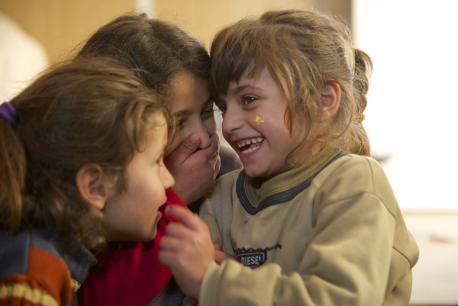 Safa (right), 6, laughs with her twin sister, Marwa (left), and 9-year-old sister, Aya (centre), in their family's caravan, in the Za'atari refugee camp,