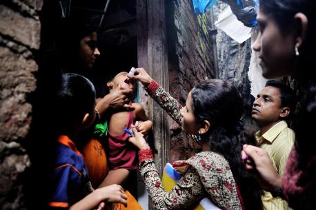A boy is given a dose of oral polio immunization by a woman. 