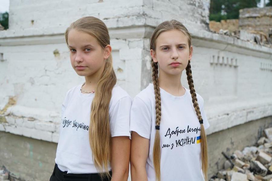Sisters Liliya, 11, and Nelya, 13, stand in front of their ruined school in Horenka, in the Kyiv region of Ukraine. 