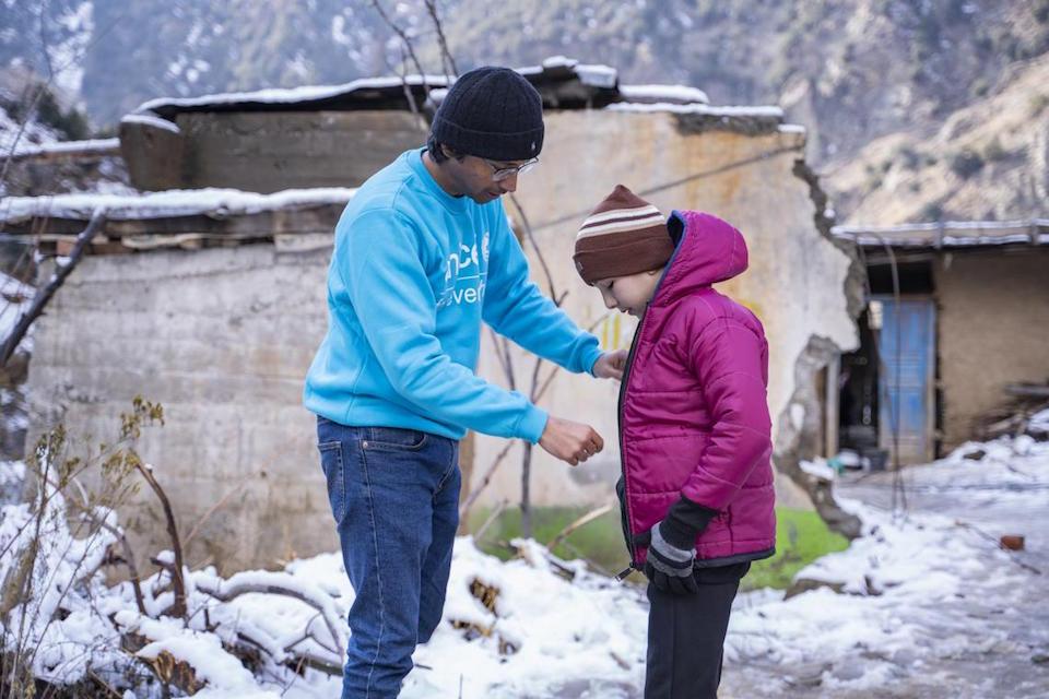 UNICEF Communication Officer – Moeed Hussain helps Noorullah wear a jacket provided to him by UNICEF in Sulool Daramdala village, Upper Dir District, Khyber Pakhtunkhwa.