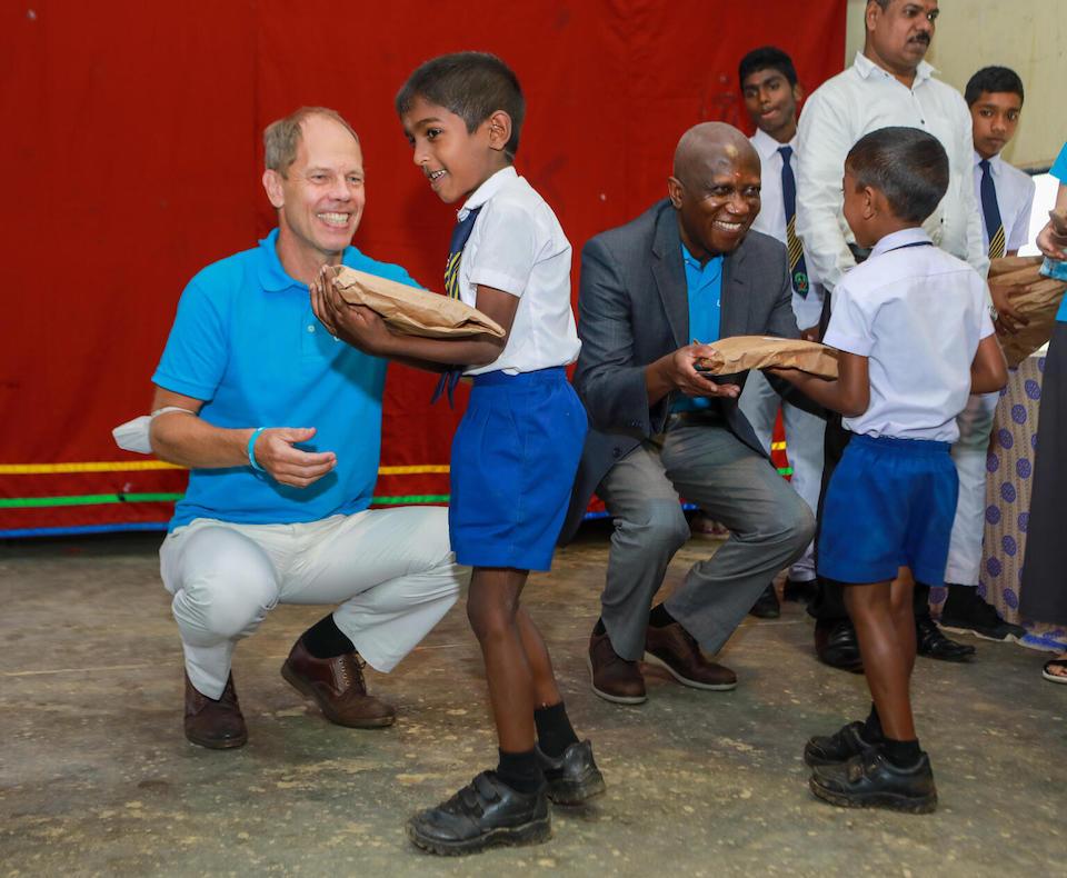 Schoolboys at Mount Jean Tamil School, Mount Jean State, Watawala, Sri Lanka, receive packages containing learning supplies from Christian Skoog, UNICEF Representative in Sri Lanka, left, and George Laryei, UNICEF Regional Director for South Asia (ROSA) in August 2022.
