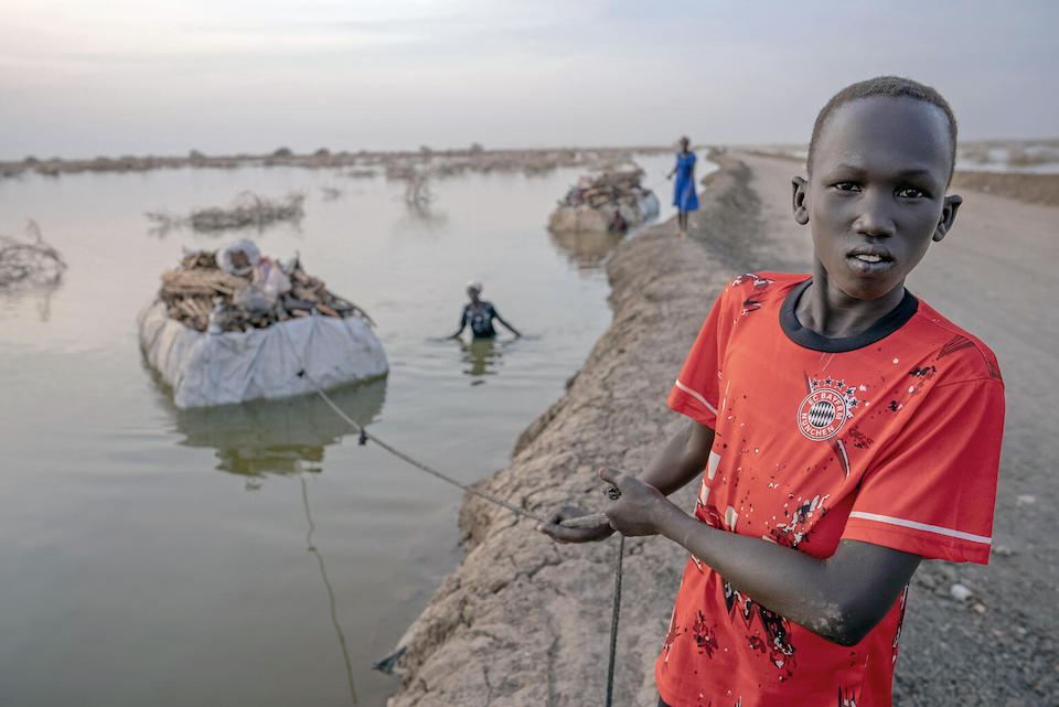 On Feb. 27, 2023, a boy drags a barge of timber through flooded fields in Bentiu, Unity State, South Sudan.