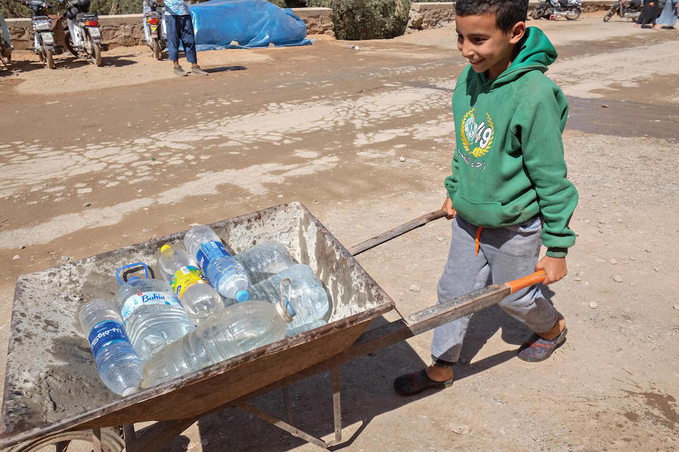 Abderahmane, 11, pushing a cart filled with bottled water, heads to the fields outside Imgdal, Morocco, where families have taken refuge since their village was destroyed by a powerful earthquake.