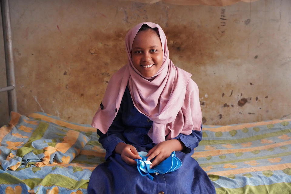 Malaz, 14, of Sudan holds reusable sanitary towels provided by UNICEF. She is staying with her family at a temporary shelter for people internally displaced by the war.