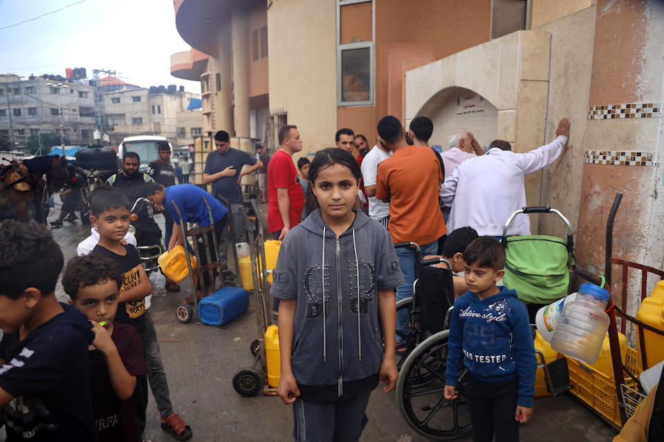 Wafaa, from Gaza City, waits her turn to fill empty plastic water containers with drinking water for her family.