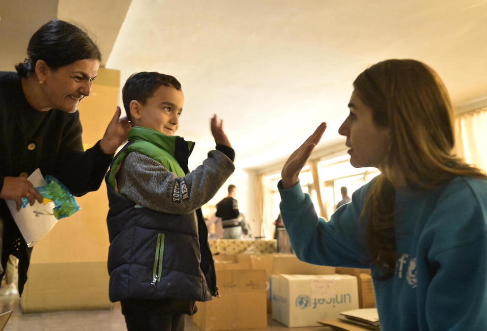 A young boy high-fives a UNICEF staff person at an assistance distribution center in Armenia providing emergency supplies to refugees from Nagorno-Karabakh.