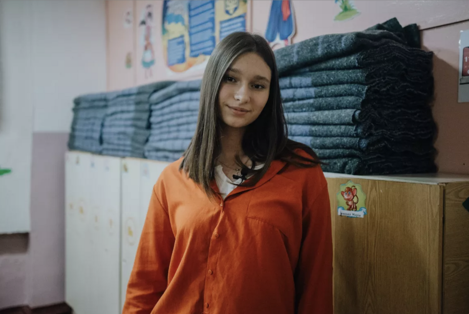 In Puzhaykove, Ukraine, Daryna, 15, stands in front of a pile of blankets purchased by her school with a grant from UNICEF at her school in 