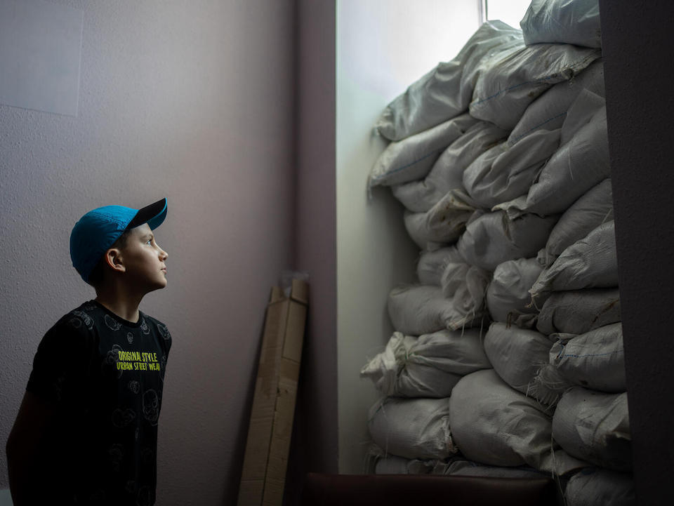 Eleven-year-old Illya of Kherson looks out a window covered with a pile of sandbags while waiting for a train that will take his family west, where they will move in with relatives.
