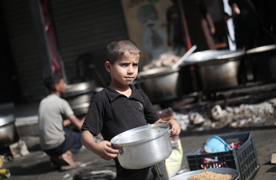 An 8-year-old holds a bowl waiting to be filled with free food in the city of Rafah, southern Gaza Strip on Nov. 26, 2023.