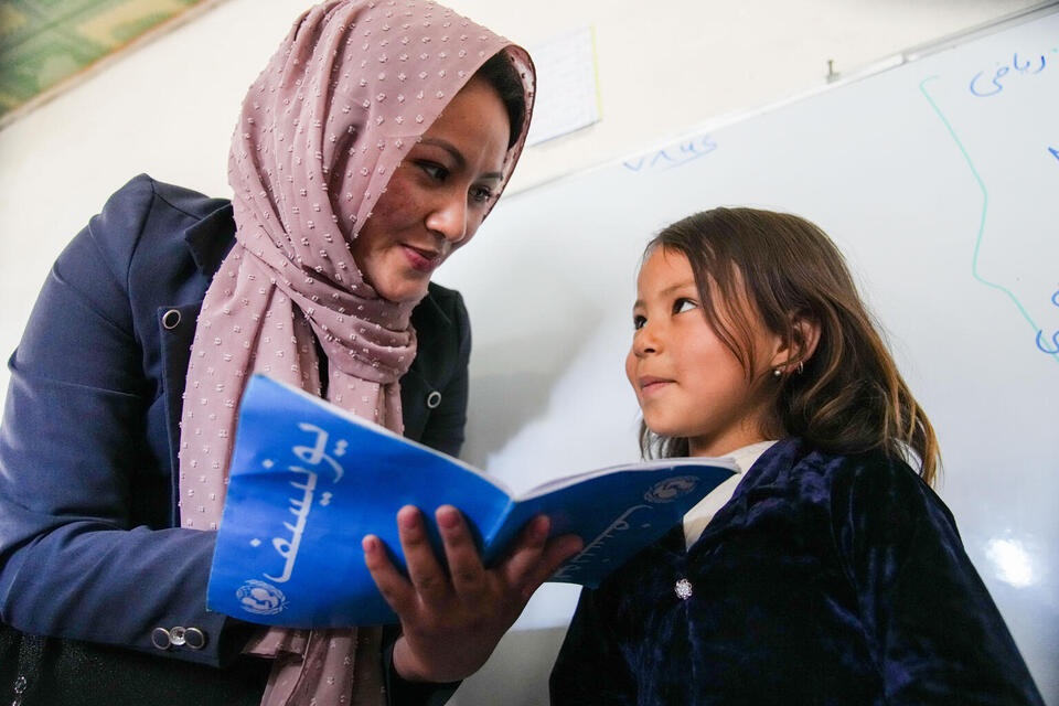 Teacher Farzana, 23, reviews homework with Baran, 7, at a UNICEF-supported community-based education class in Bamyan Province, Afghanistan, in May 2023.