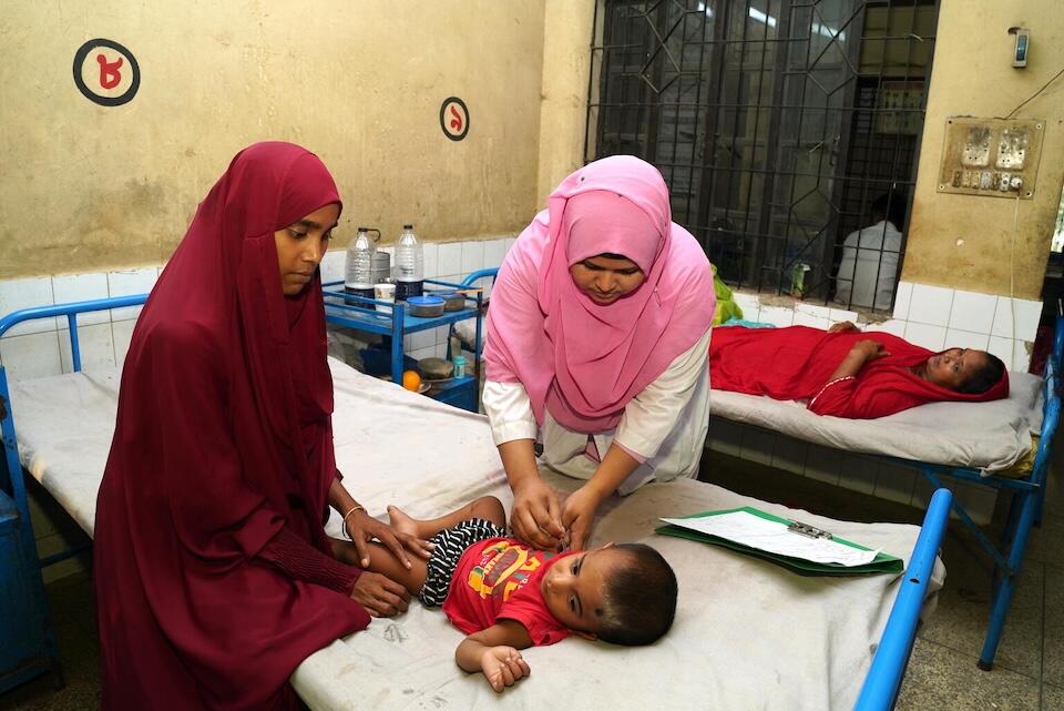Razia treats an ill child while on duty at the Upazila Health Complex in Mirzapur, Tangail.
