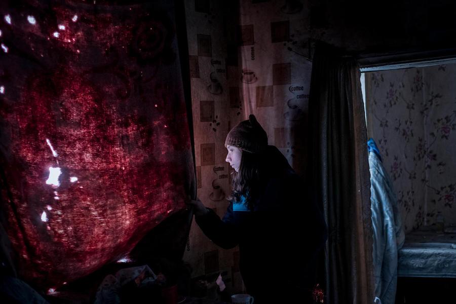 Anya, 13, looks out the window of her old, now destroyed home in Avdiivka, Donetsk Oblast, eastern Ukraine in November 2017.