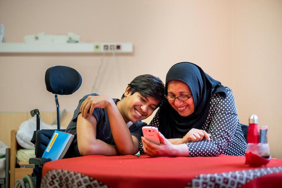 Sajad, 16, takes a break from his German homework to watch a video his mother in September 2017. Refugees from Iraq, they live in an abandoned senior citizens hospital in Vienna. 