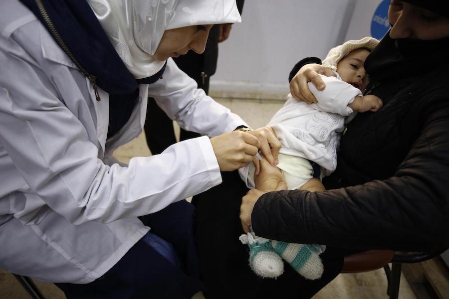 In December 2018, an infant is vaccinated at the Eastern Douma Primary Health Center operated by the local department of health and supported by UNICEF in East Ghouta, Syria.