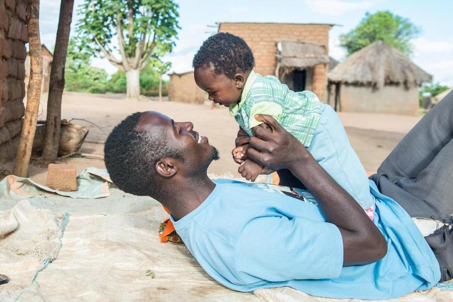 Lukas Phiri plays with his 4-month-old daughter Faith in Kholowa Village, Katete District in Zambia's Eastern Province.
