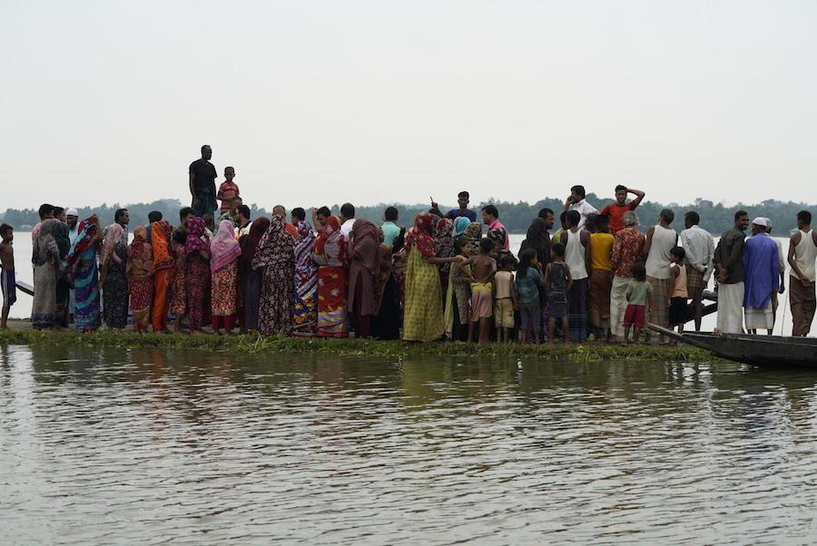Families crowd onto a dry strip of road as they flee their flooded homes in Sunamganj, Bangladesh on May 23, 2022. 