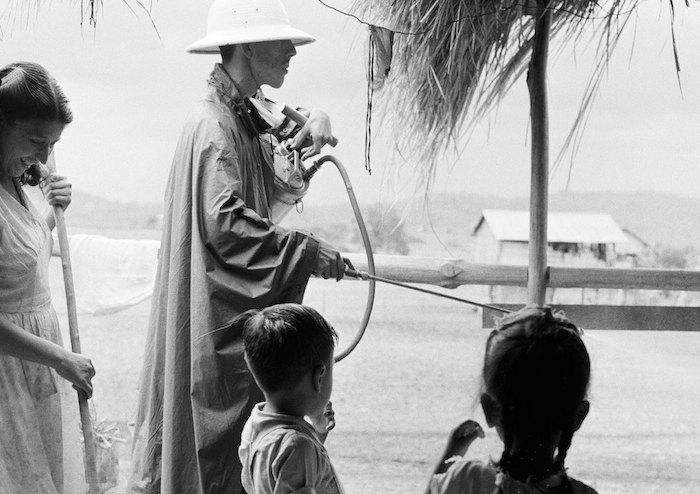 In 1958 in the Guayaquil coastal region of Ecuador, a malaria campaign worker sprays the outside of a house with UNICEF-supplied insecticide to kill the malaria-bearing mosquito.