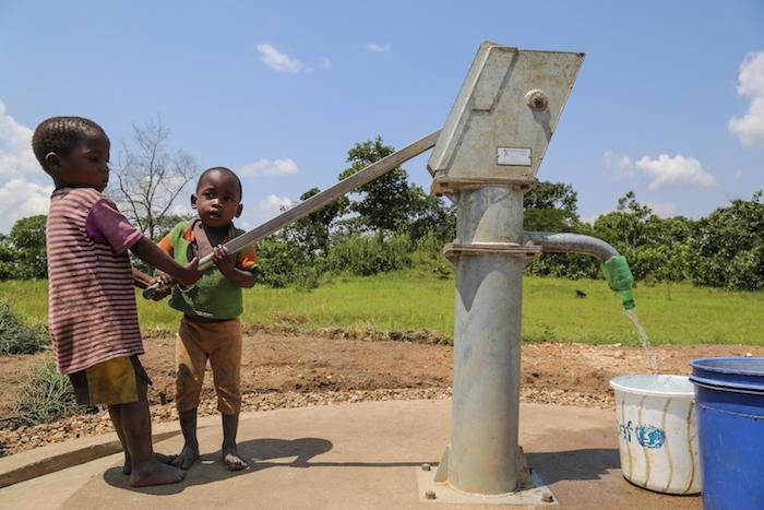 Three-year-old Innocent (right) and a friend use a new hand pump to fill a container with clean, safe water in Rutana Province, Burundi in January 2018.
