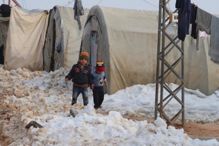 UNICEF Winter for Syrian Children: On 21 December 2016 at the Al-Nour IDP camp in rural Idlib, Syrian Arab Republic, two children walk in the snow and mud.