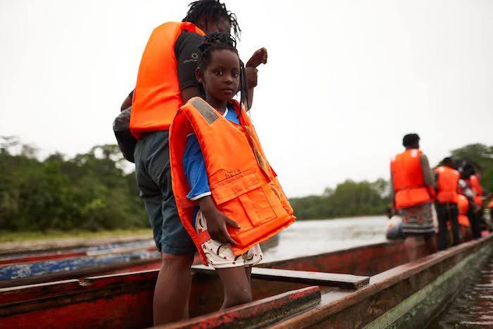 A migrant girl who has arrived in Panama having journeyed through the Darién Gap is helped into a boat.