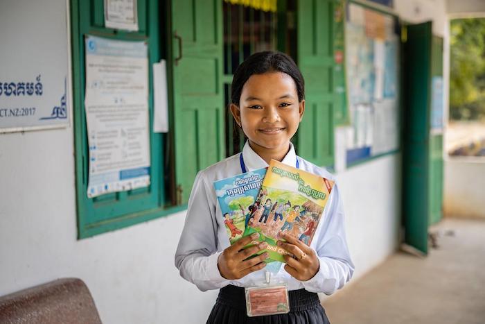 Voeurn, a Grade 6 student at Ang Run Primary School, in Tramkak District, Takeo Province, Cambodia, holding informational booklets on menstrual hygiene management and other matters provided to students through a UNICEF-supported program.