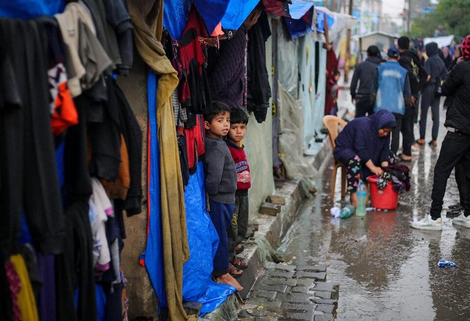 On a rainy day in the city of Rafah in the southern Gaza Strip, children stand outside the tent where they are staying with their families after being displaced by violence. 