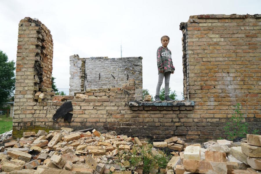 Ten-year-old Anya stands on the ruins of the village school in Horenka, in the Kyiv region, which became part of the front line in Feb. 2022 and was heavily damaged by shelling. 