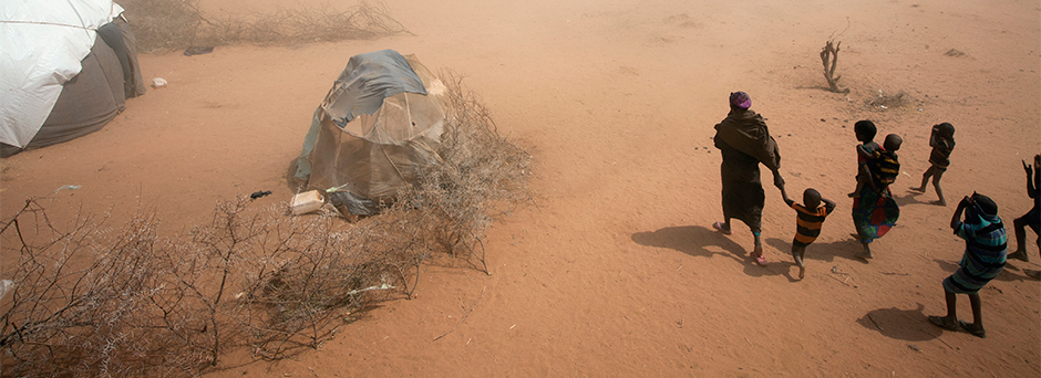 On 9 July, a woman and several children walk through a dust storm to their tent, in an area for new arrivals in the Dagahaley refugee camp in North Eastern Province, near the Kenya-Somalia border. The camp is among three that comprise the Dadaab camps, lo