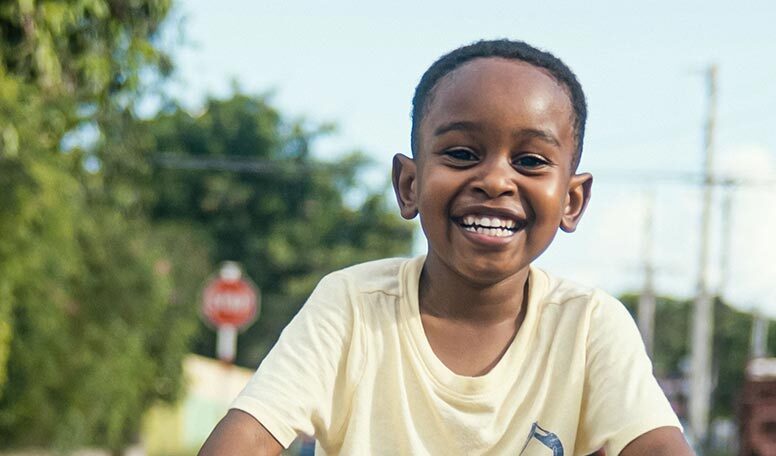 Ari Safiatou rides a bike on the street while smiling.