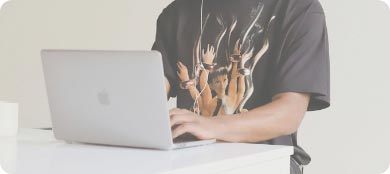 torso view of someone in dark t-shirt typing on a laptop