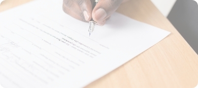 a hand holds a pen, signing a contract document