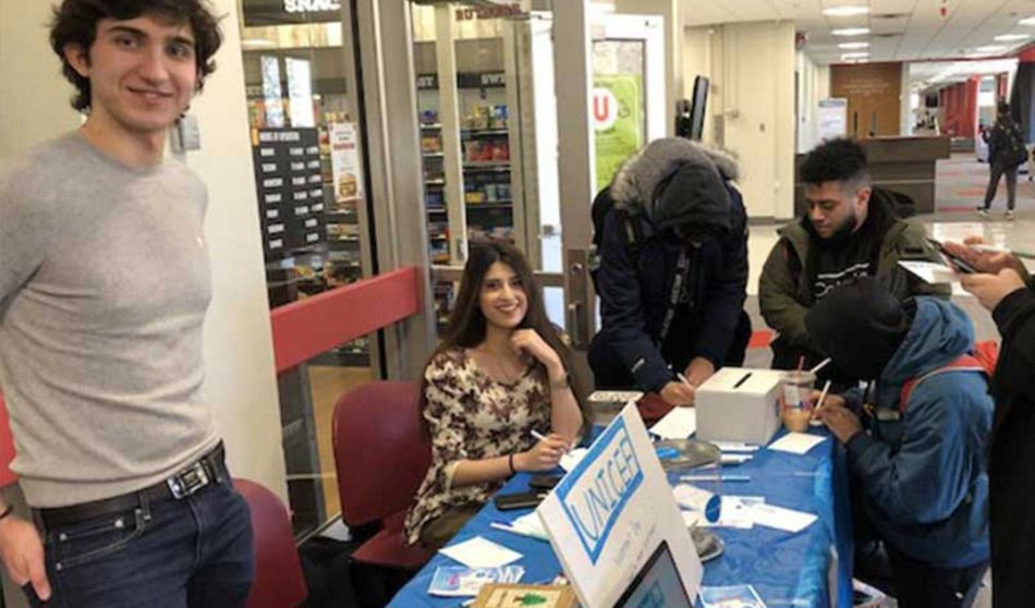 College students sit at a table while hosting a pottery painting event at Rutgers University—Newark.