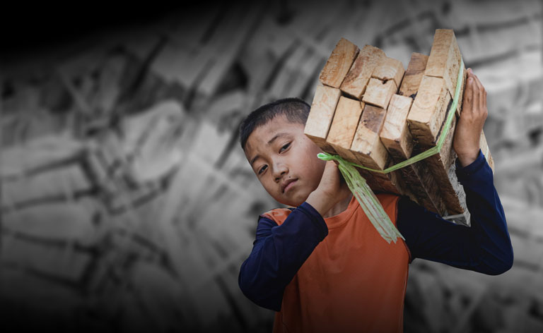 Young boy carring a stack of lumber