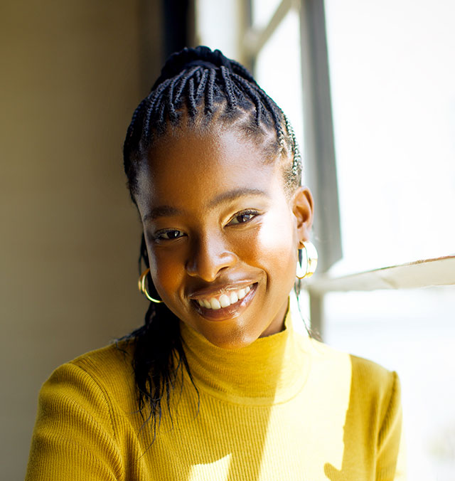 Headshot of Amanda Gorman in a yellow turtleneck, her braids hanging over her right shoulder.