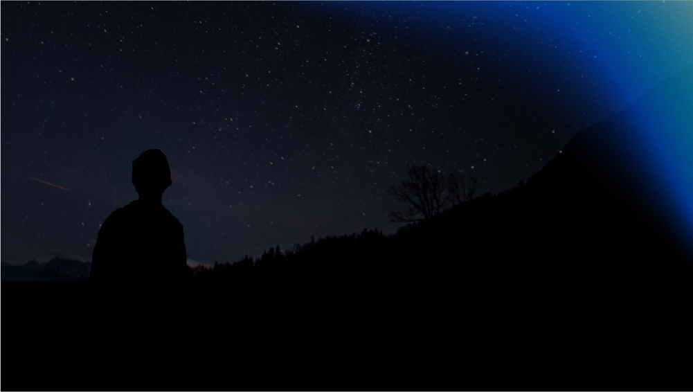 Silhouette of a person looking up at the sky, with rays of moonshine glowing at the top
