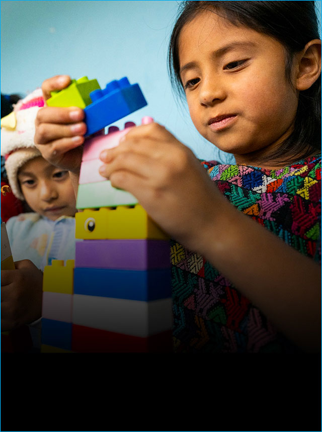 A child plays with oversized lego blocks that she stacks.
