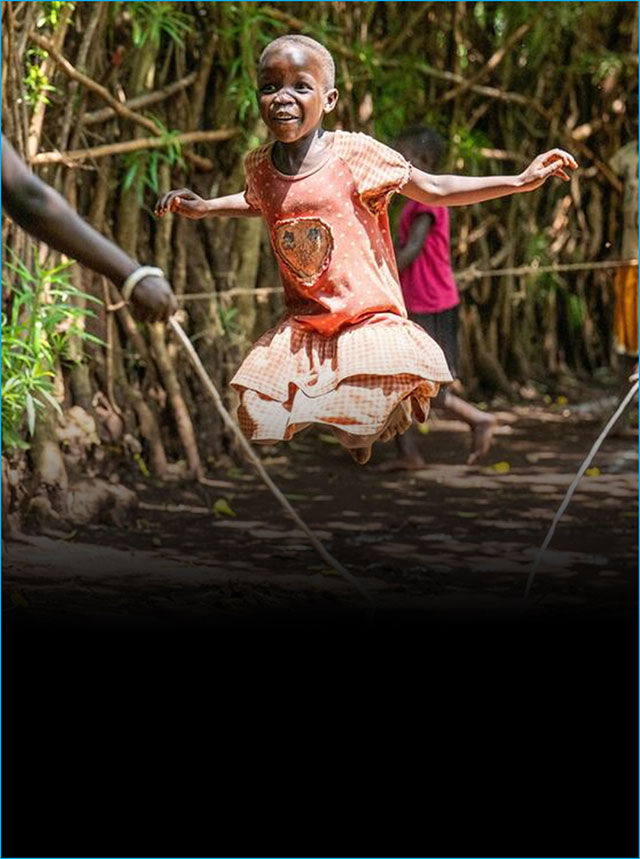 Two children play football in a heavily wooded area.