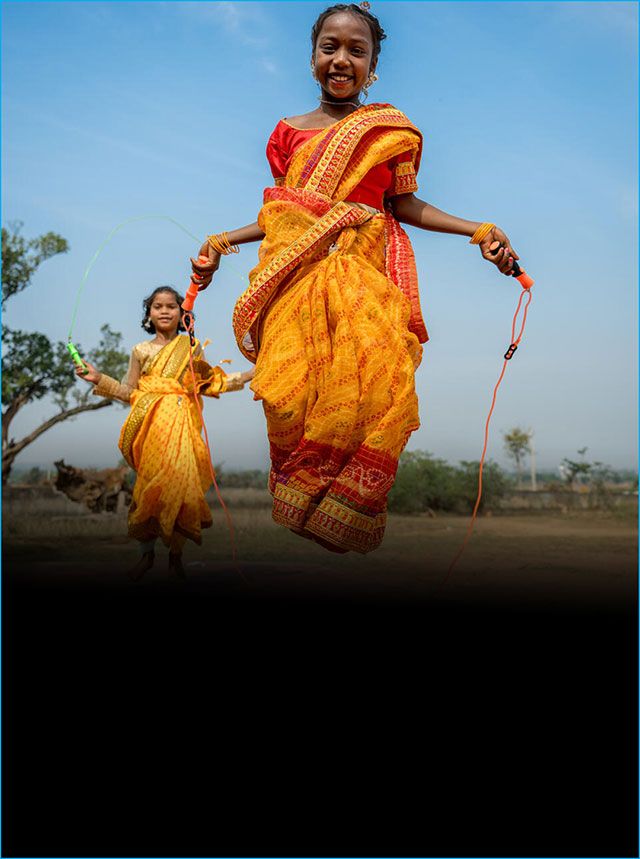 A girl in a sari jumps rope outside.