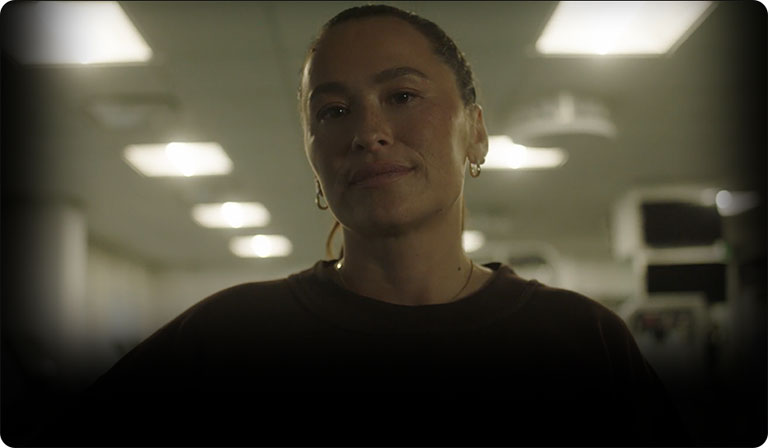 Ali Riley, a woman with hair pulled back, stands akimbo in a warehouse.