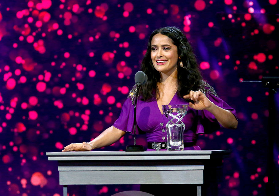 Salma Hayek gives a speech at a podium