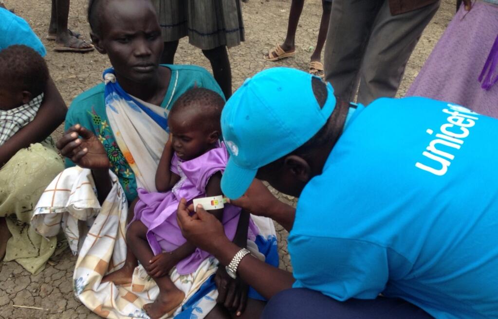 A health worker uses a MUAC arm measurement tape to screen a South Sudanese child for malnutrition.