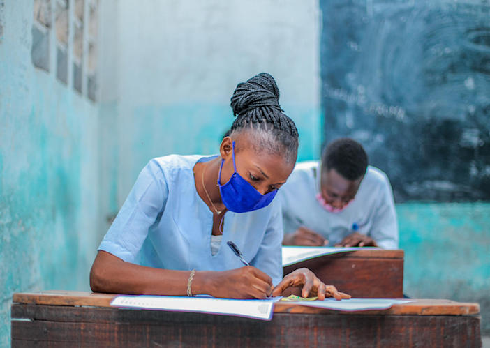 Elodie, a high school senior in Kinshasa, Democratic Republic of Congo, sits for her exam while wearing a mask to prevent the spread of COVID-19.