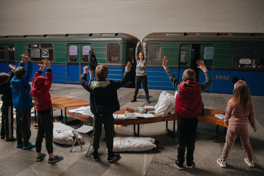 Volunteer teacher Yuliia Kruhlaia, 41, leads children in a warm-up exercise on the platform of a Kharkiv metro station. 
